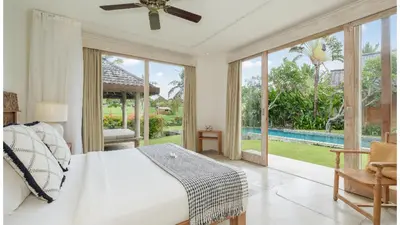 a bedroom with a bed and a view of a pool at Villa Alea by Villa Finder in Kerobokan