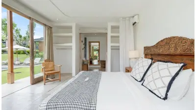 a bedroom with a bed and a large window at Villa Alea by Villa Finder in Kerobokan
