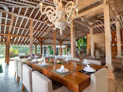 a dining room with a long wooden table and chairs at Villa Mannao by Villa Finder in Kerobokan