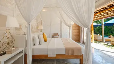 a bedroom with a bed with white curtains at Villa Little Mannao by Villa Finder in Kerobokan