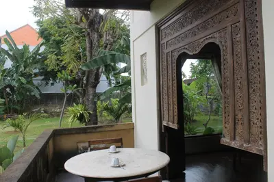 an open door to a room with a table and a window at Puri Kutat Lestari in Sanur