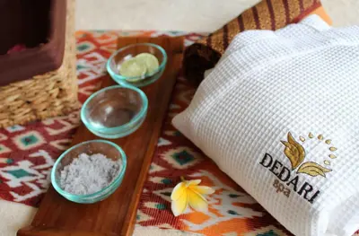 a wooden tray with three bowls of rice and a towel at Golden Tulip Jineng Resort Bali in Kuta