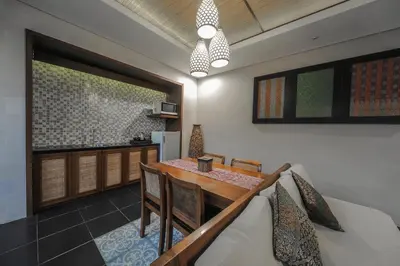 a dining room with a table and a kitchen at Gaing Mas Jimbaran Villas by Gaing Mas Group in Jimbaran