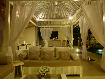 a couch in a living room with white curtains at La Dolce Villa in Seminyak