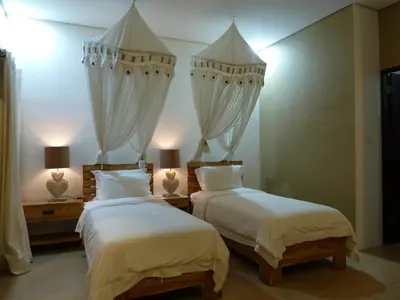 two beds in a room with white curtains at La Dolce Villa in Seminyak