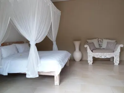 a bedroom with a canopy bed and a chair at La Dolce Villa in Seminyak