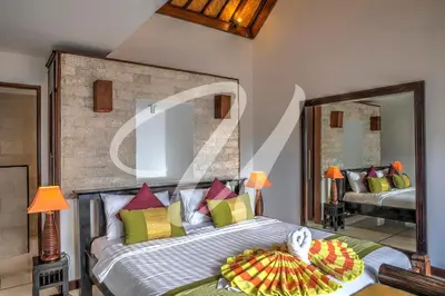 a bedroom with a large bed and a mirror at Vila Ultima Bali in Seminyak