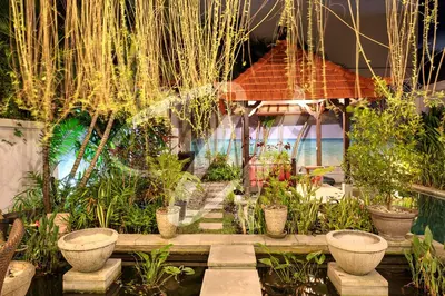 a garden with plants and a house in the background at Vila Ultima Bali in Seminyak