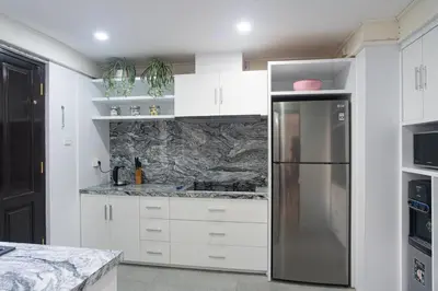 a kitchen with white cabinets and a stainless steel refrigerator at Villa Kibbi in Seminyak