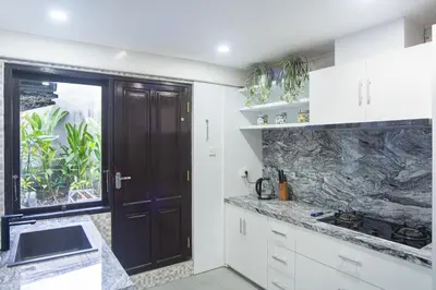 a kitchen with white cabinets and a black door at Villa Kibbi in Seminyak