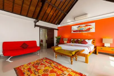 a bedroom with a bed and a red couch at Villa Kibbi in Seminyak