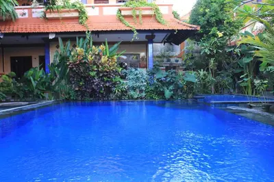 a large blue swimming pool in front of a building at Losmen Cempaka 3 in Kuta