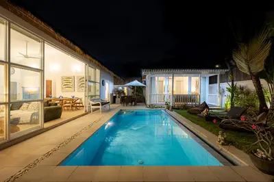 a swimming pool in the backyard of a house at night at Villa Blue Pearl by Optimum Bali Villas in Seminyak