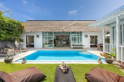 a woman laying on the grass next to a swimming pool at Villa Blue Pearl by Optimum Bali Villas in Seminyak
