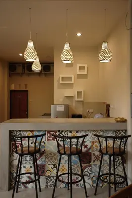 a kitchen with two bar stools and three lights at Kuta Suci Guesthouse in Kuta