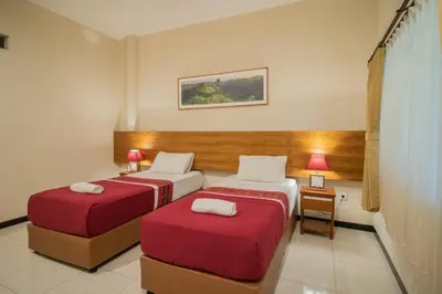 a hotel room with two beds with red sheets at Kuta Suci Guesthouse in Kuta