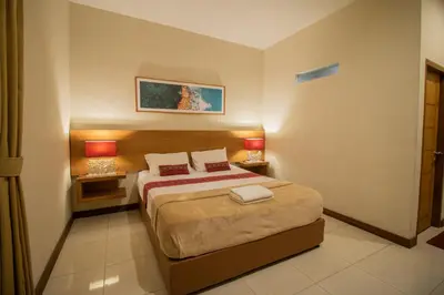 a bedroom with a bed with two lamps on it at Kuta Suci Guesthouse in Kuta
