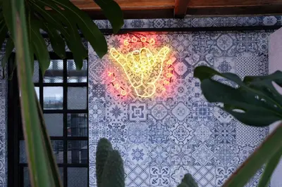 a neon sign on a wall with a window at H-ostel Bali in Kuta