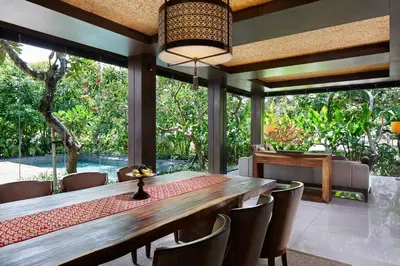 a dining room with a large wooden table and chairs at The Anvaya Beach Resort Bali in Kuta