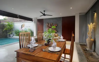 a dining room with a wooden table and chairs at Sudha Villa Bali Baik-Baik in Seminyak