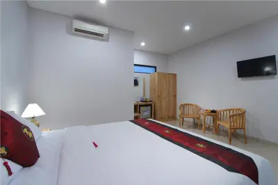 a bedroom with a large white bed and a table at Sleepwell Seminyak in Seminyak