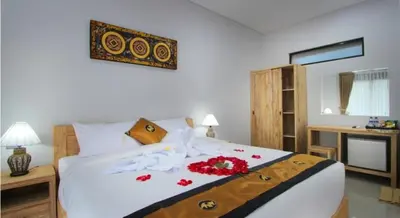 a bedroom with a large white bed with flowers on it at Sleepwell Seminyak in Seminyak
