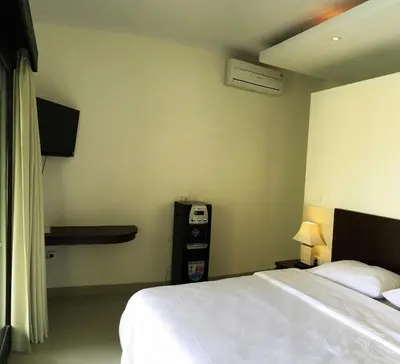a hotel room with a bed and a phone on the wall at Indah Homestay in Seminyak