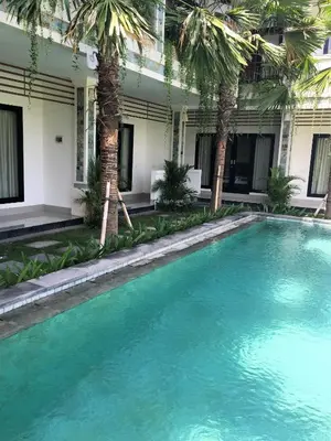 a swimming pool in a courtyard with palm trees at Indah Homestay in Seminyak