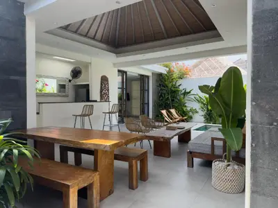 a living room with a wooden table and benches at Aster Villa Seminyak in Seminyak