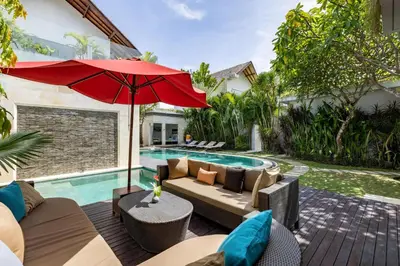a patio with a couch and an umbrella next to a swimming pool at Villa Belle Seminyak by Exotic Bali Properties in Seminyak