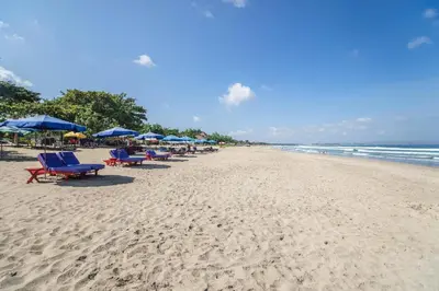 a beach with chairs and umbrellas and the ocean at Swiss-Belexpress Kuta Legian in Kuta