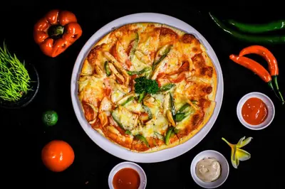 a pizza in a plate on a table with peppers at Swiss-Belexpress Kuta Legian in Kuta