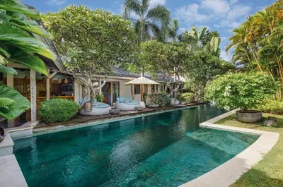 a swimming pool in front of a house with trees at Villa Cinta Damai - Stunning & Stylish 4BR Luxury Villa in the Heart of Seminyak, Just a 10-Min Walk to the Beach in Seminyak