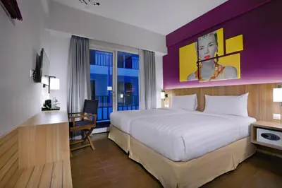 a hotel room with a large bed and a desk at Fame Hotel Sunset Road in Kuta