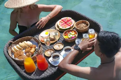 a man and woman sitting at a table with a tray of food at 3BR Villa Hari - Special Stay Bonus - Minggu Villas Seminyak in Seminyak