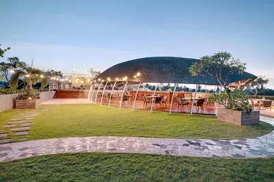 a restaurant with tables and chairs in a park at FOX Hotel Jimbaran Beach Bali in Jimbaran