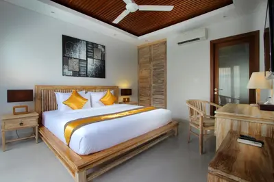a bedroom with a large bed and a desk at The Murdha Villa in Seminyak