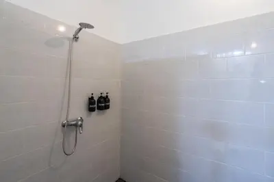a bathroom with a shower with bottles on the wall at Pennylane Villa in Seminyak
