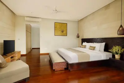 a bedroom with a large bed and a flat screen tv at Villa Tenang by Nakula in Canggu