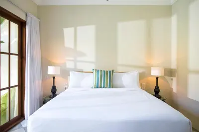 a bedroom with a large white bed with two lamps at Villa Mandala in Seminyak