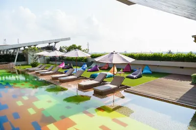 a pool with lounge chairs and umbrellas on the grass at Fairfield by Marriott Bali South Kuta in Kuta
