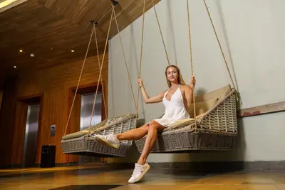 a woman in a white dress sitting on a swing at Fairfield by Marriott Bali South Kuta in Kuta