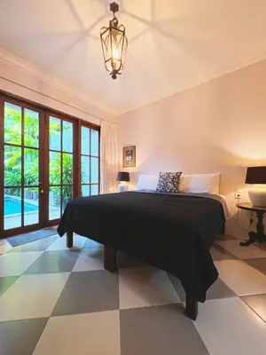 a bedroom with a large bed and a chandelier at Villa Antiga 2 in Seminyak