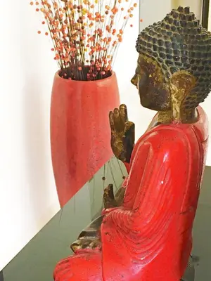 a red vase with a statue in front of a mirror at Flora Apartment Bali in Seminyak