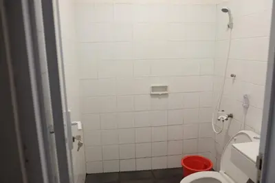 a bathroom with a toilet and a red bucket at Palm Garden Kuta in Kuta