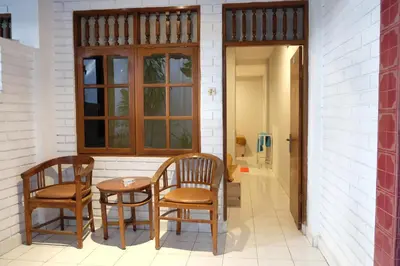 a porch with two chairs and a table at Palm Garden Kuta in Kuta