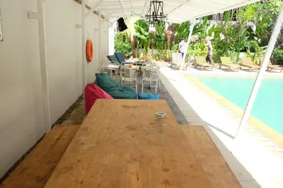 a living room with a wooden table next to a pool at Palm Garden Kuta in Kuta