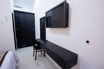a bedroom with a desk with a television on the wall at Asta House in Kuta