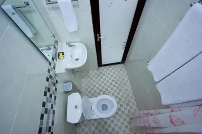a bathroom with two toilets and a sink and a mirror at Asta House in Kuta