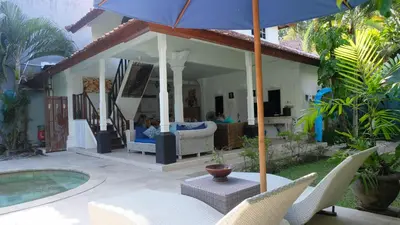 a patio with a table and chairs and an umbrella at Villa Alam Biru Gardenia in Seminyak